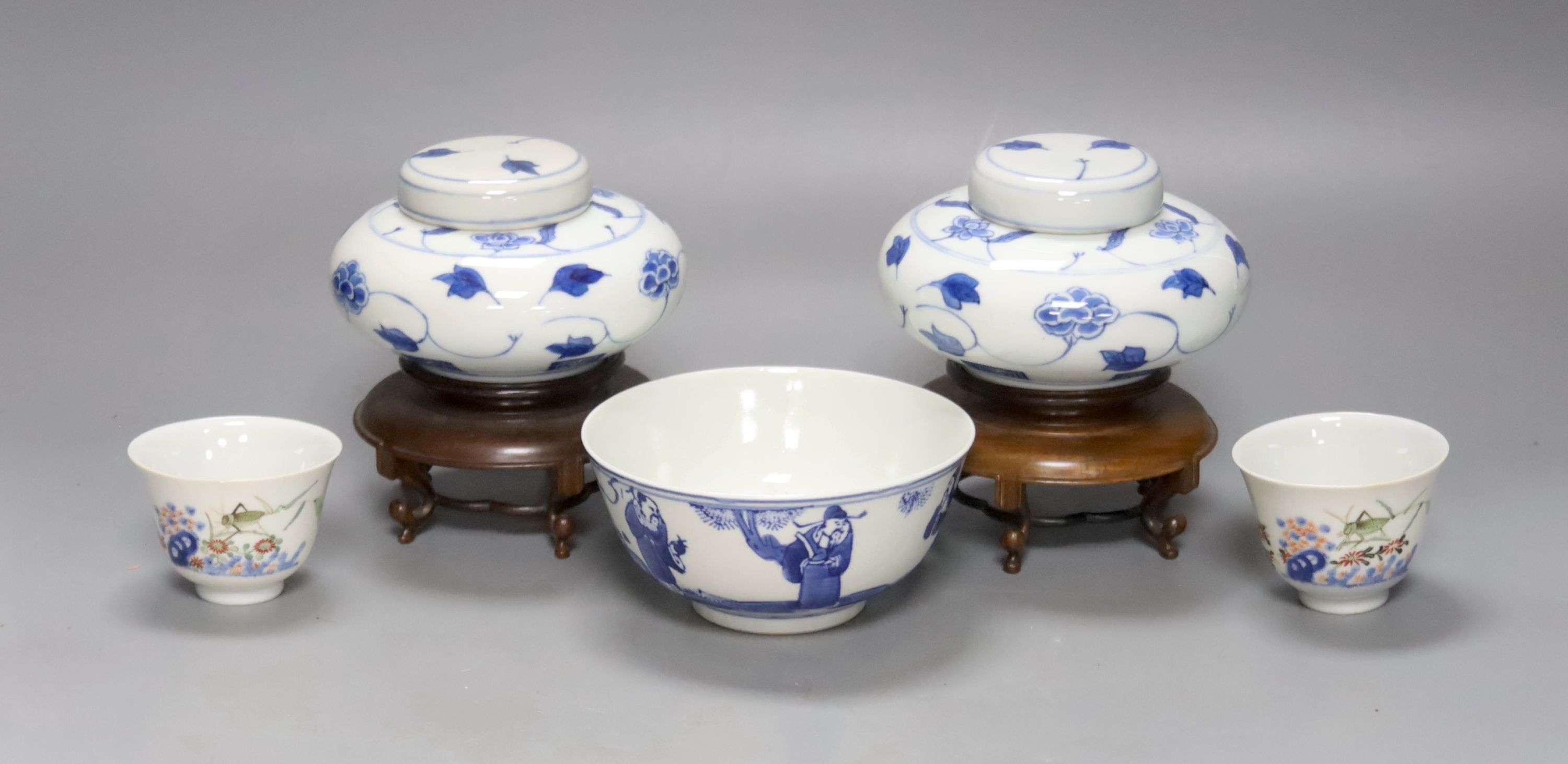 A pair of Chinese blue and white jars and covers, 6.5cm, on wood stands, a Chinese blue and white bowl and two small enamelled wine cups